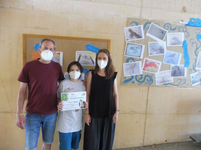 El niño Alejandro Pascual, en compañía de sus padres, muestra su diploma de ganador de un primer premio.